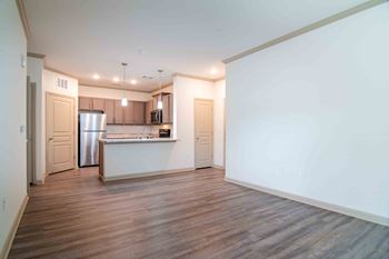 an empty living room with a kitchen with a refrigerator and a sink at Century New Holland, Gainesville